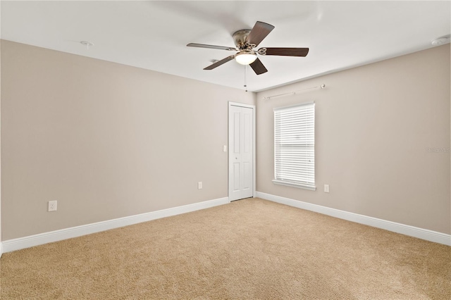 empty room featuring ceiling fan, baseboards, and light colored carpet