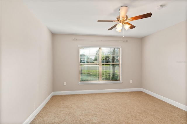 carpeted spare room with ceiling fan and baseboards