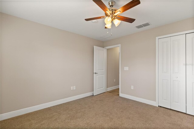 unfurnished bedroom with a closet, visible vents, a ceiling fan, carpet flooring, and baseboards