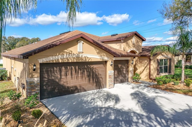 mediterranean / spanish-style house with a garage, stone siding, driveway, and stucco siding