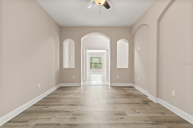 empty room featuring ceiling fan, baseboards, and wood finished floors