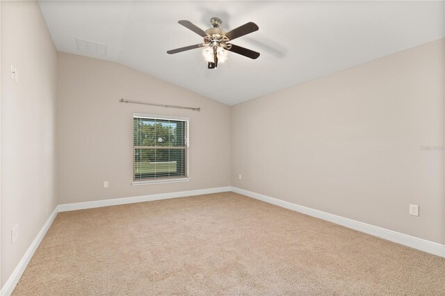 spare room with vaulted ceiling, carpet floors, a ceiling fan, and baseboards