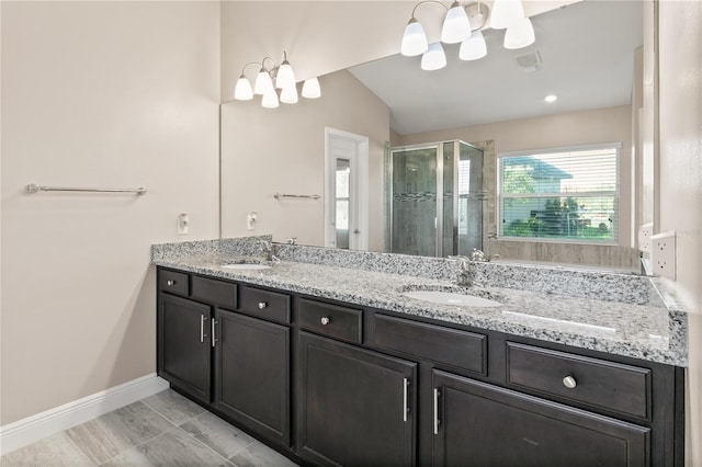 bathroom featuring a chandelier, double vanity, a stall shower, and a sink