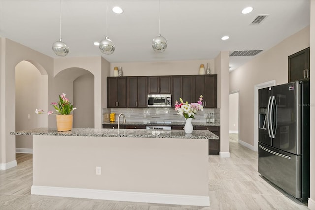 kitchen with visible vents, dark brown cabinets, stainless steel microwave, and refrigerator with ice dispenser