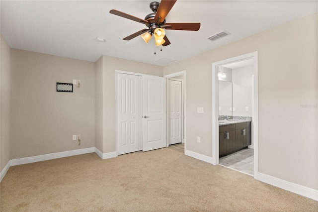 unfurnished bedroom with light carpet, a sink, visible vents, baseboards, and a closet