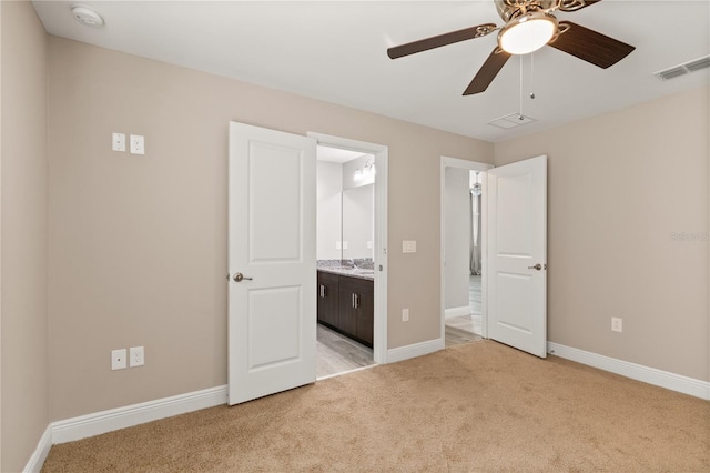 unfurnished bedroom with ensuite bathroom, light carpet, a ceiling fan, visible vents, and baseboards