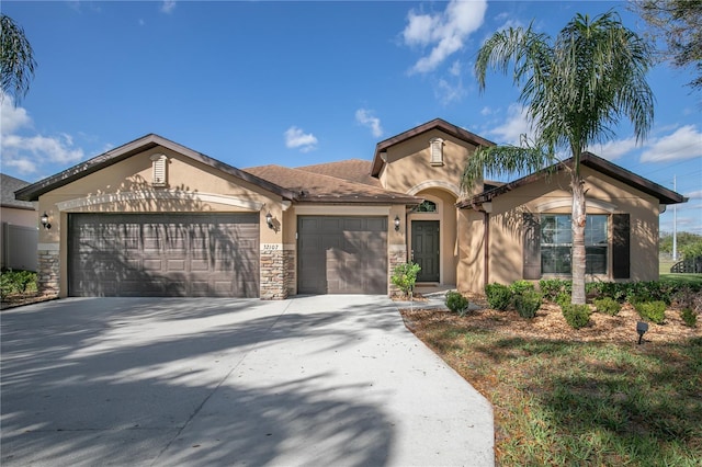 view of front of house featuring a garage, stone siding, driveway, and stucco siding