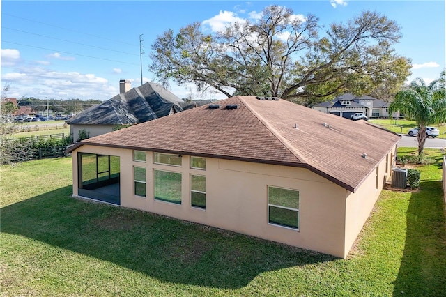 view of side of property with a shingled roof, central air condition unit, a lawn, and stucco siding