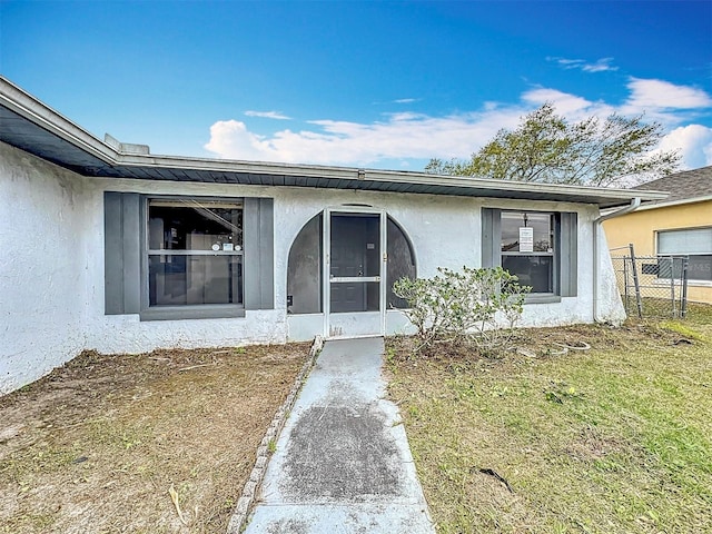 entrance to property with a yard and stucco siding