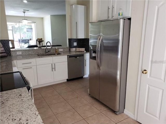 kitchen with appliances with stainless steel finishes, a sink, white cabinetry, and light stone countertops