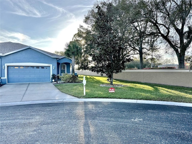 ranch-style house with a garage, concrete driveway, a front lawn, and stucco siding