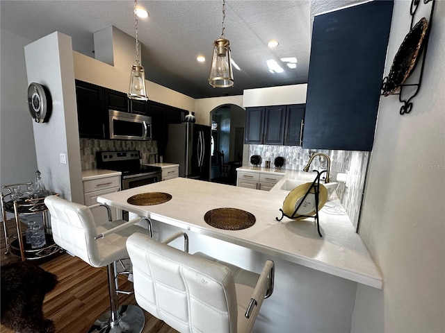 12209 Putter Green Ct, New Port Richey, FL 34654 - kitchen featuring appliances with stainless steel finishes, arched walkways, tasteful backsplash, light countertops, and a textured ceiling