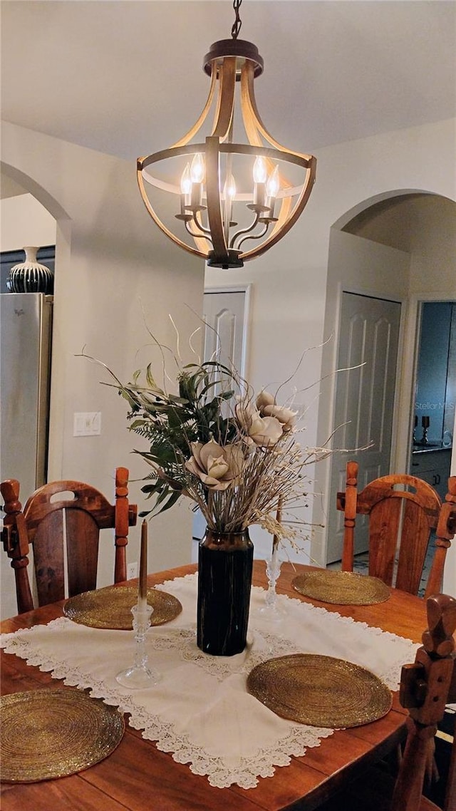 12209 Putter Green Ct, New Port Richey, FL 34654 - dining room featuring arched walkways, a chandelier, and wood finished floors
