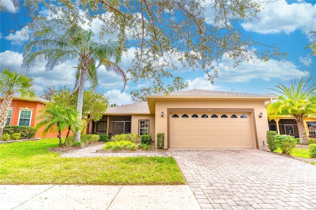 view of front of home featuring decorative driveway, an attached garage, stucco siding, and a front yard