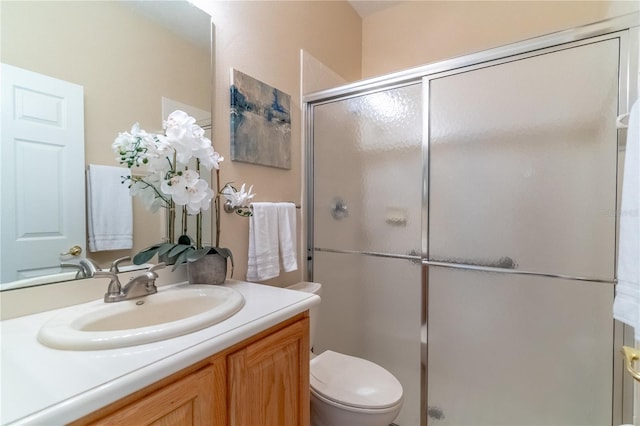 bathroom featuring toilet, a stall shower, and vanity