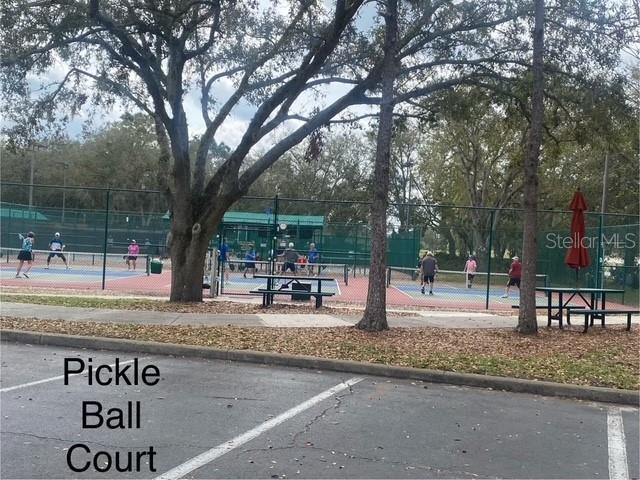 surrounding community with a tennis court and fence