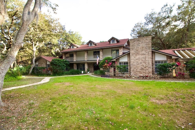 view of front of property featuring brick siding, a front lawn, and a balcony