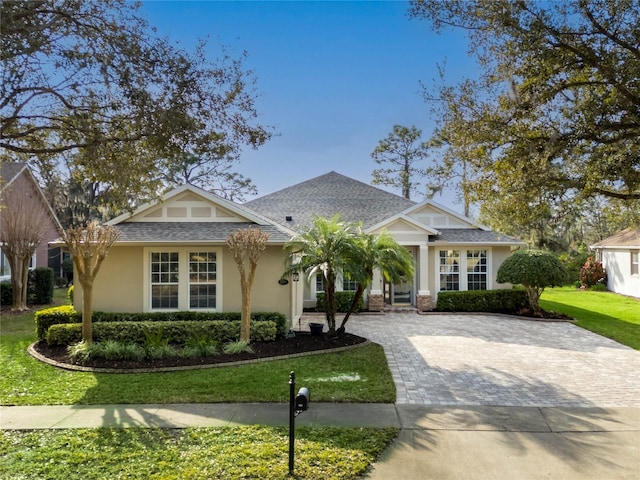 view of front of property with a shingled roof, driveway, a front lawn, and stucco siding