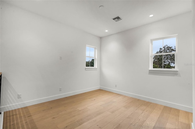 empty room featuring light wood-type flooring, visible vents, baseboards, and recessed lighting