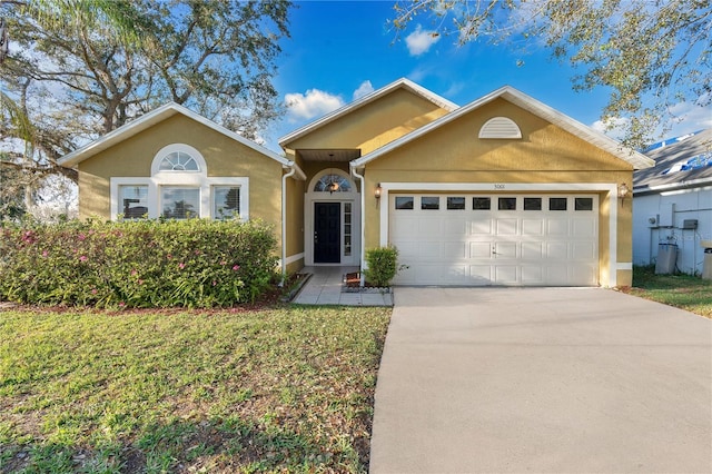 single story home with a front lawn, concrete driveway, an attached garage, and stucco siding