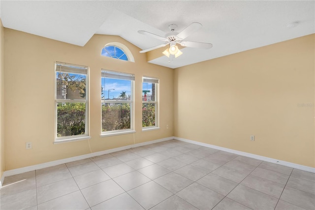 spare room with vaulted ceiling, ceiling fan, light tile patterned floors, and baseboards