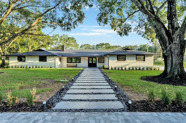 ranch-style home with brick siding, a chimney, and a front yard