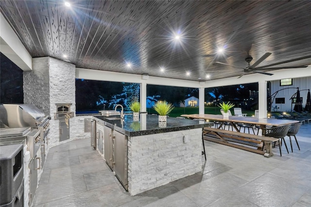 view of patio with an outdoor kitchen, outdoor wet bar, area for grilling, a sink, and a ceiling fan