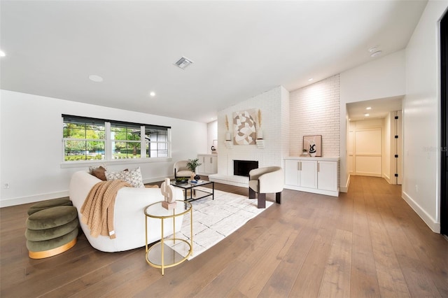 living area featuring lofted ceiling, light wood-style flooring, recessed lighting, a fireplace, and visible vents