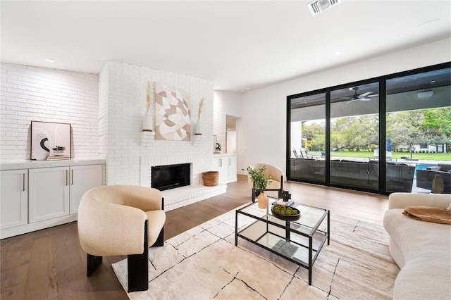 living room with ceiling fan, light wood-type flooring, a fireplace, and visible vents