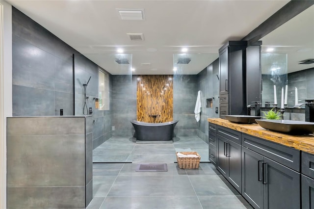 bathroom with visible vents, walk in shower, a sink, and tile walls