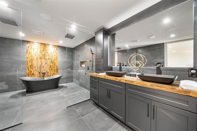 bathroom with visible vents, a sink, tile walls, and double vanity