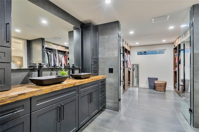 full bath with visible vents, a sink, a spacious closet, and double vanity