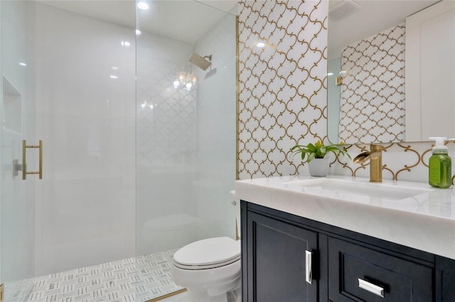 bathroom with tiled shower, vanity, and toilet