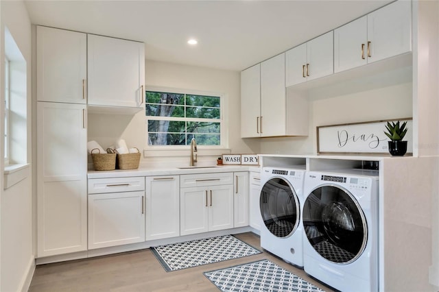 laundry area featuring light wood-style flooring, recessed lighting, a sink, cabinet space, and washing machine and clothes dryer