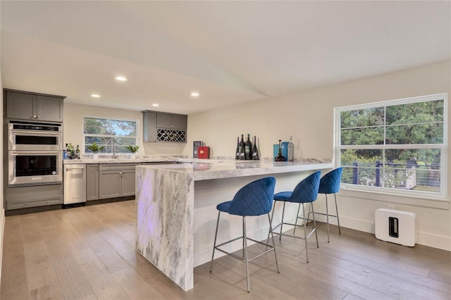 kitchen featuring a peninsula, gray cabinets, and stainless steel double oven