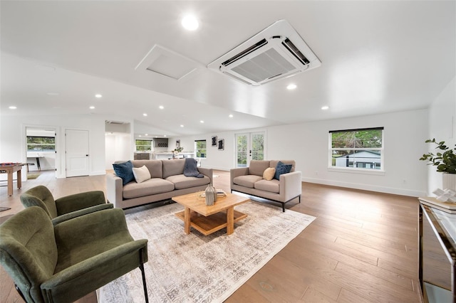 living area featuring baseboards, lofted ceiling, light wood-style flooring, a wall mounted AC, and recessed lighting