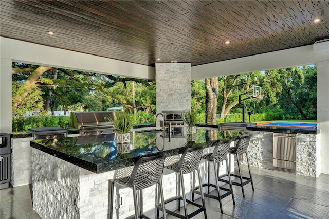 view of patio featuring outdoor wet bar, exterior kitchen, and area for grilling