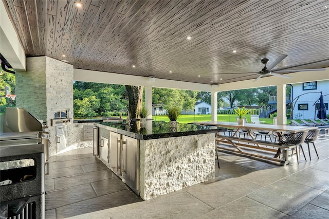 view of patio / terrace featuring outdoor wet bar, a sink, a ceiling fan, exterior kitchen, and grilling area