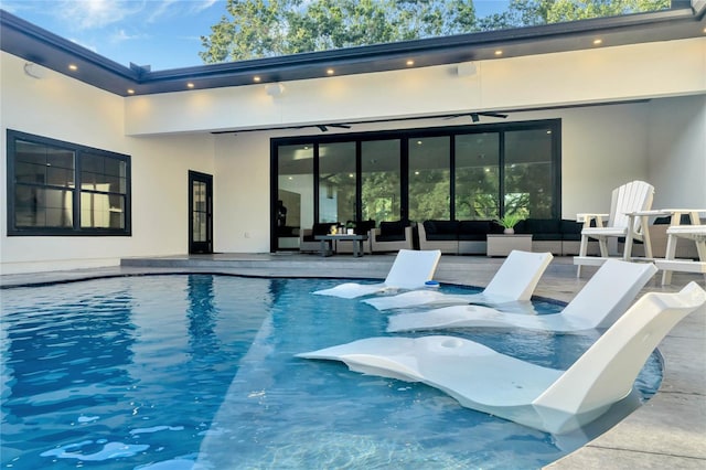 pool with an outdoor hangout area, a ceiling fan, and a patio