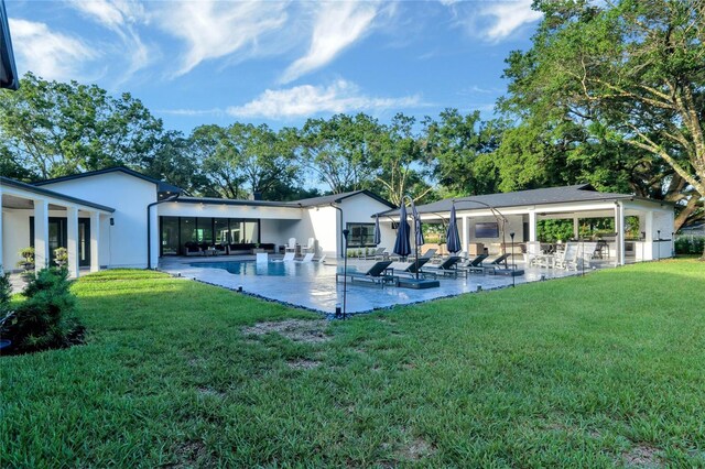 rear view of house with a patio, a yard, and an outdoor pool