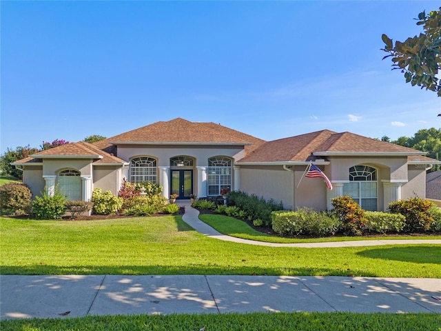 mediterranean / spanish-style home with stucco siding, a front yard, and french doors