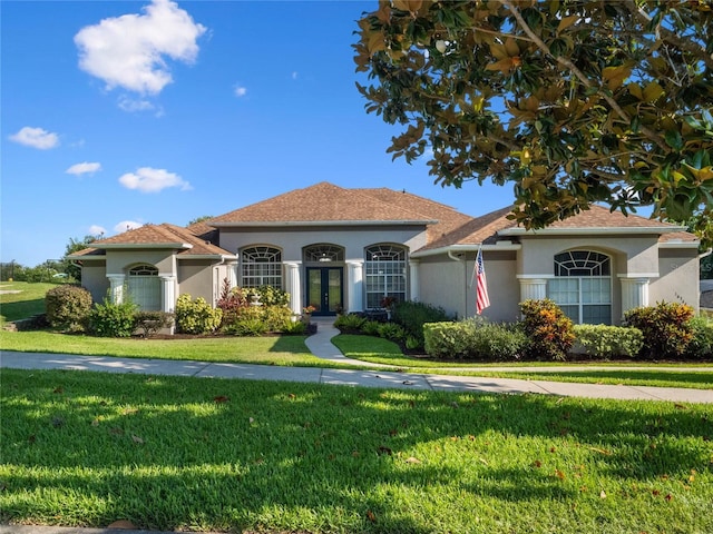 mediterranean / spanish-style home with stucco siding, french doors, and a front yard