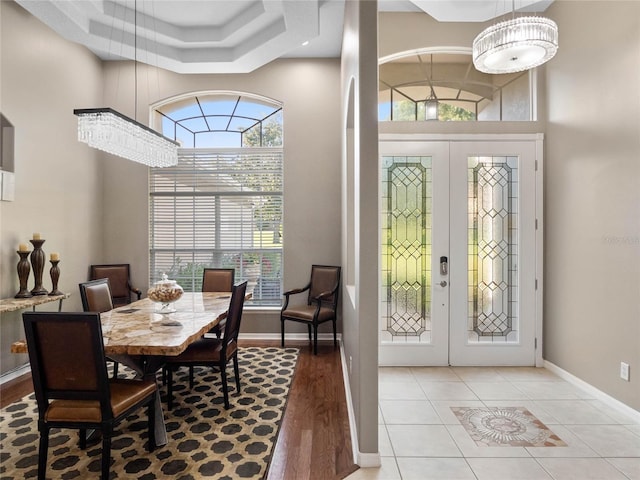 entrance foyer featuring a towering ceiling, light tile patterned floors, baseboards, and french doors