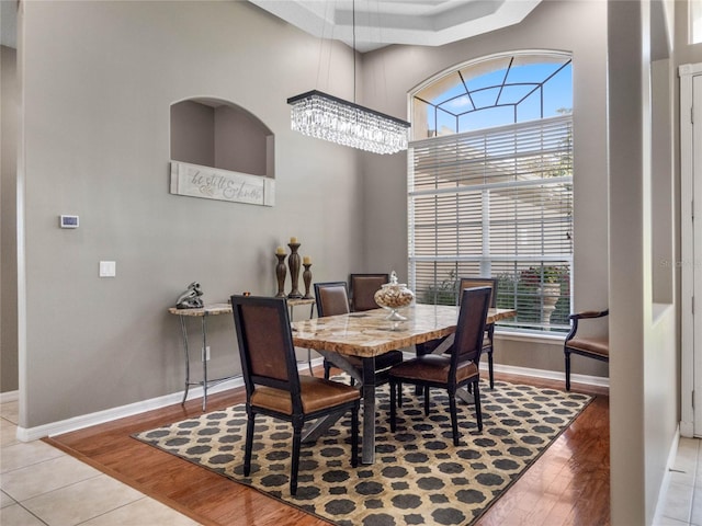 dining room with a chandelier, a high ceiling, light wood-style flooring, and baseboards