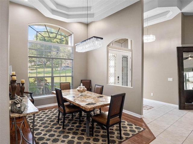 dining space with a towering ceiling, light tile patterned floors, and baseboards