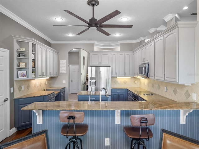 kitchen featuring a breakfast bar area, white cabinets, blue cabinetry, appliances with stainless steel finishes, and open shelves