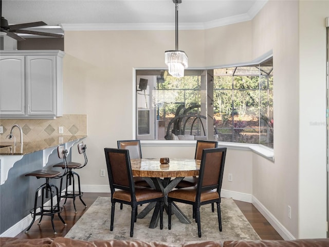 dining area featuring dark wood-style floors, baseboards, and crown molding