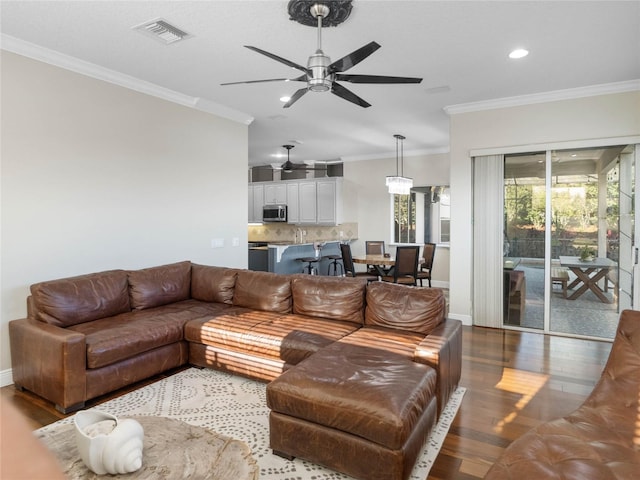 living area featuring ornamental molding, wood finished floors, visible vents, and baseboards