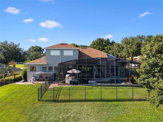 rear view of house with a yard, stucco siding, fence, a lanai, and a swimming pool