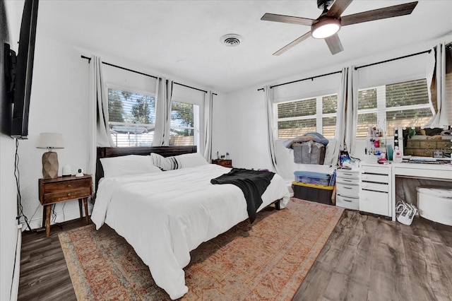 bedroom with dark wood-style floors, ceiling fan, and visible vents